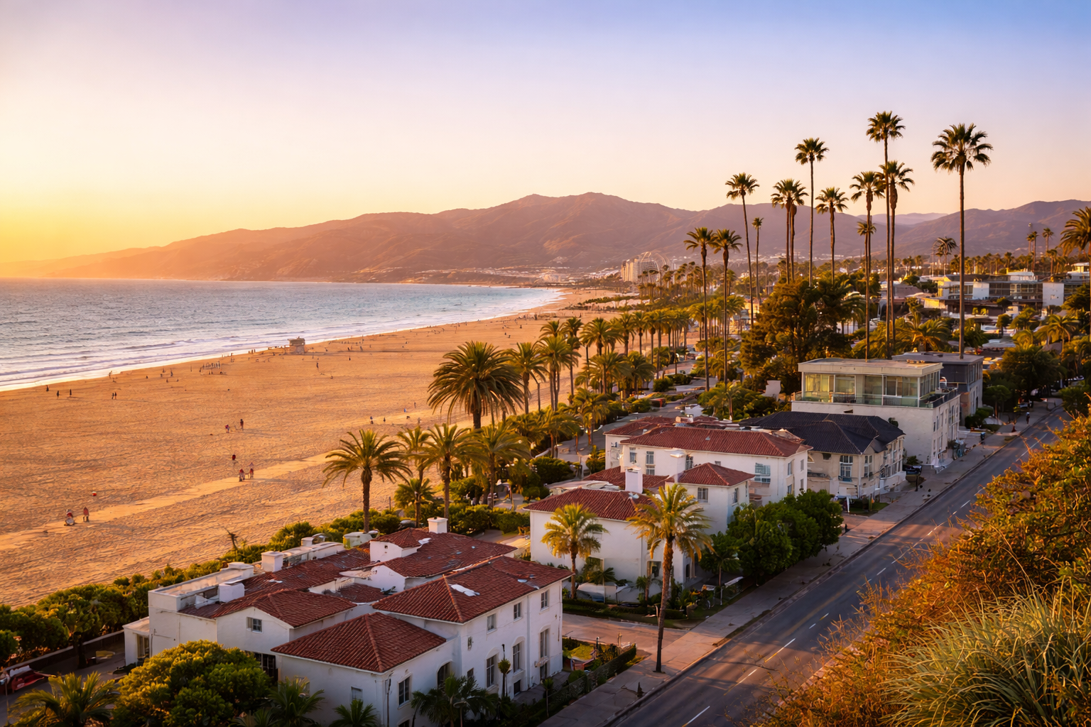 Aerial view of Santa Monica beach at sunset with palm-lined streets and coastal mountain views.