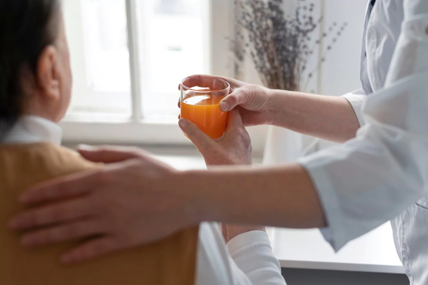 Caregiver handing a glass of juice to a senior client - Contact Care to Stay Home